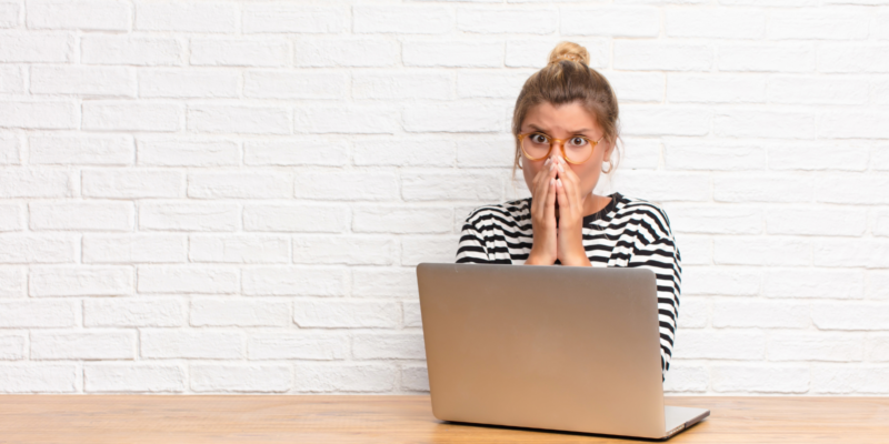 Woman sitting in front of her laptop looking shocked