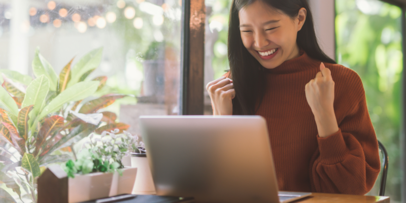 Young Asian woman celebrate success or happy pose with laptop