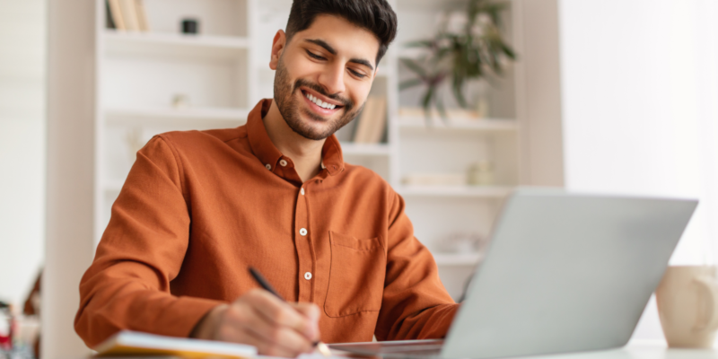 man smiling while working on laptop