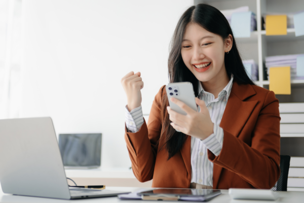 Asian business woman delighted and happy with their work, getting good news on phone